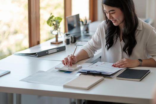 Business woman using calculator and laptop for do math finance on wooden desk in office and business working background, tax, accounting, statistics and analytic research concept