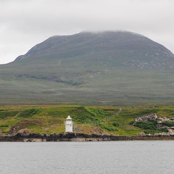 Carragh an t-Sruith lighthouse in the Sound of Islay near Feolin, Jura sits under the mountain shrouded in cloud, Hebrides, Scotland, UK