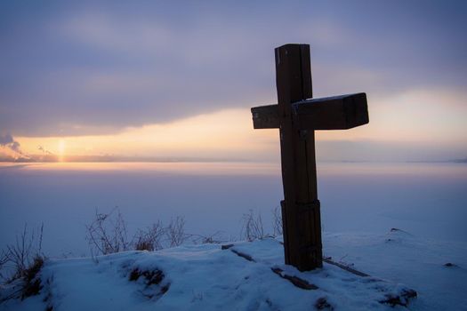 wooden Orthodox cross on the background of the Kama river in winter.