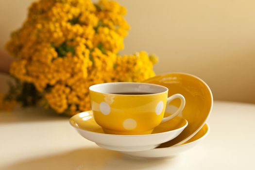 yellow cup levitation with black tea. retro tea-set with flowers. vintage ceramic mug and plates on the table