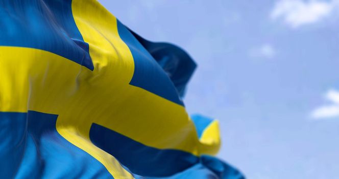 Detail of the national flag of Sweden waving in the wind on a clear day. Democracy and politics. North European country. Selective focus.