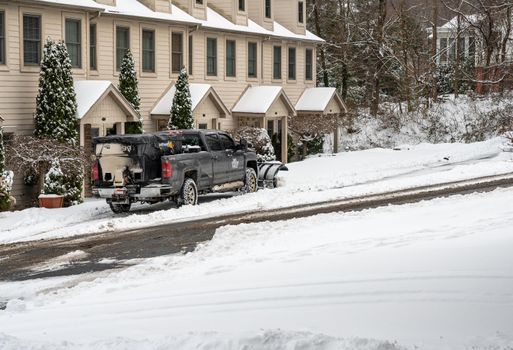 Morgantown, WV - 17 January 2022: Truck with snow plow blade attachment clearing residential street after snow storm