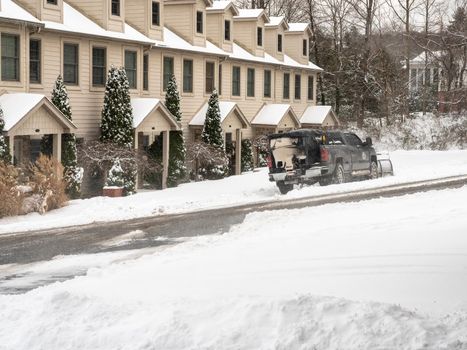Morgantown, WV - 17 January 2022: Truck with snow plow blade attachment clearing residential street after snow storm