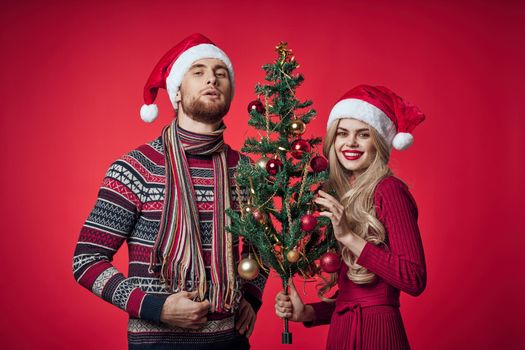 cheerful young couple new year tree decoration red background. High quality photo