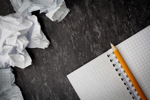 Crumpled and torn paper on the table. Torn piece of notebook. Paper trash. Full basket of notes. Notepad and pencil on crumpled paper background.