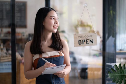 Portrait of Woman barista cafe owner smile while cafe open. SME entrepreneur seller business concept