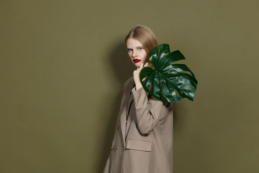 fashionable woman green palm leaf coat bright makeup studio model unaltered. High quality photo