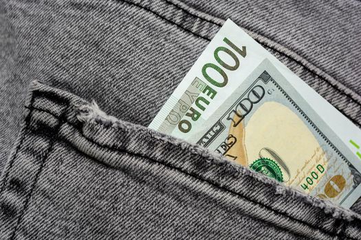 American hundred dollars and 100 euros in the back pocket of frayed jeans. Choice in currency exchange. Selective focus.