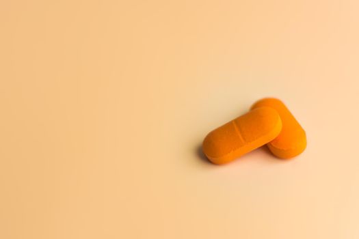 Two large orange pills on a gentle orange background. Selective focus. Medicine and health care theme.