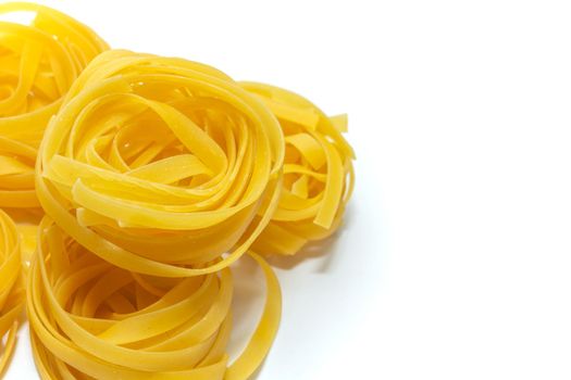 Tagliatelle. Glossy Italian pasta made from durum wheat flour on a white background. Close-up, top view. Selective focus. Food products.