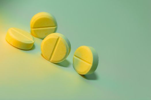 Yellow pills on a light green background. Place for your text. Close-up. Selective focus. Healthcare and medical concept.