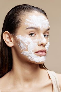 Beautiful Woman applying a soothing face mask skin care beige background. High quality photo