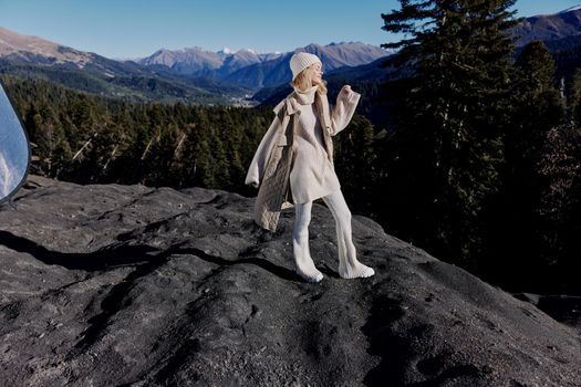 young woman in autumn clothes stands on a rock landscape blue sky relaxation. High quality photo