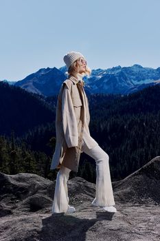 woman in autumn clothes stands on a rock blue sky relaxation. High quality photo