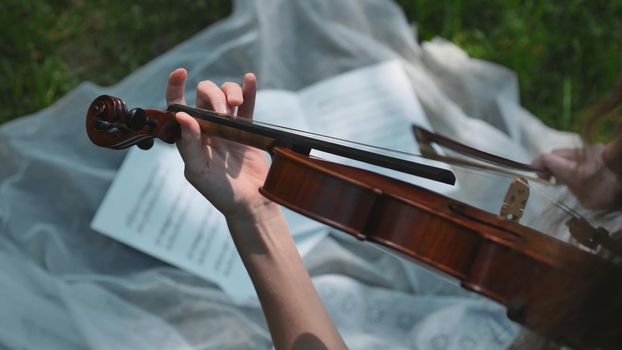 The girl plays the cello on the notes in the summer park