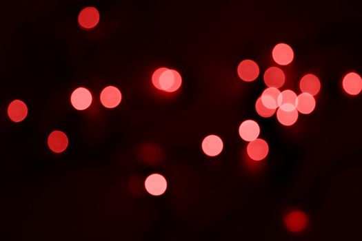 Defocused bokeh lights on black background, an abstract naturally blurred backdrop for Valentine's Day or birthday party. Festive light texture. Pink and red garland in blur. Overlay effect for design