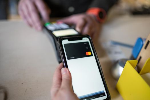 Shopping with mobile phone payment. Customer using contactless payment. Female hand paying with NFC technology on phone. Paying contactless with digital wallet. Pay by card on NFC payment terminal.