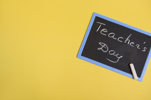 Flat lay of a chalckboard with inscription Teachers Day on a yellow background with space for text