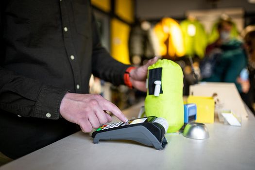 Salesman holds payment terminal while holding receipt for completing purchase. Hands close up. Concept of NFC, business and banking transactions. Payment terminal with paper tape. Bank terminal.