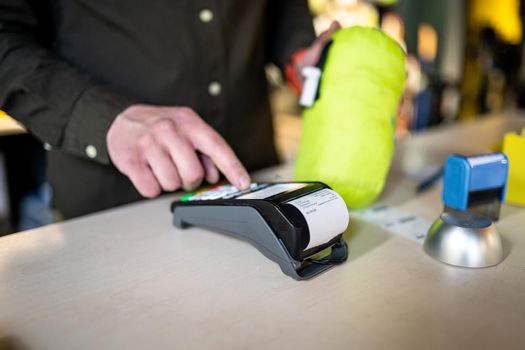 Salesman holds payment terminal while holding receipt for completing purchase. Hands close up. Concept of NFC, business and banking transactions. Payment terminal with paper tape. Bank terminal.