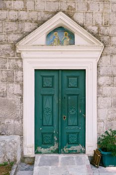 Green wooden door on the stone facade of the temple. High quality photo