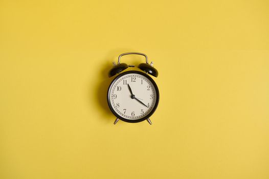 Flat lay composition of an alarm clock, on yellow background with space for text. Concept of checking time, time management, business and events