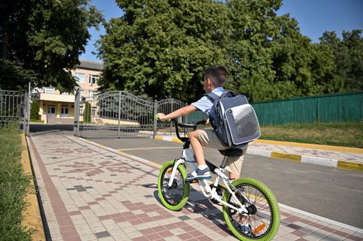 Rear view of a child on a bicycle in early morning. Boy on bike in the city. Back to school