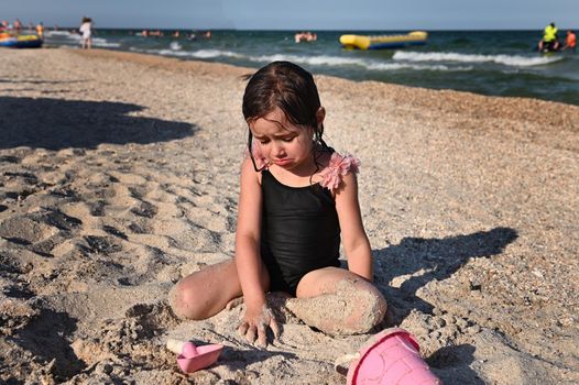 Summer holidays concept. Active lifestyles and happy summer vacations. Summer vacation. Adorable toddler girl playing with beach toys on the sandy beach.