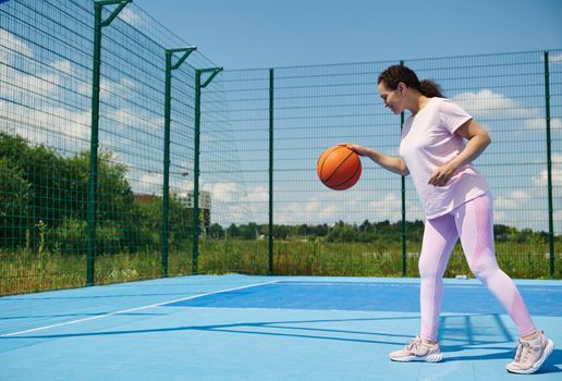 Young female basketball player stuffing a basketball ball on the court