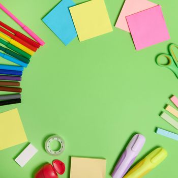 Flat lay composition with stationery office or school supplies scattered in a circle on a light green background with copy space. Teacher's day concept