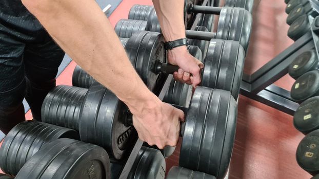 MOSCOW - 2021. Man hands holding black resin dumbbells. . High quality photo