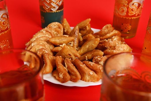 Soft focus on tasty and sweet plate full of fresh traditional Moroccan handmade Brewat sweets. Red background, copy space.