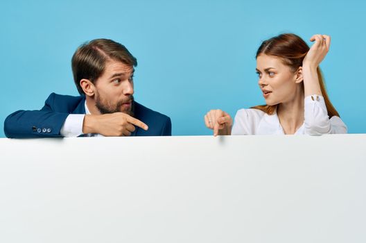 business man and woman with white mockup poster advertising sign blue background. High quality photo