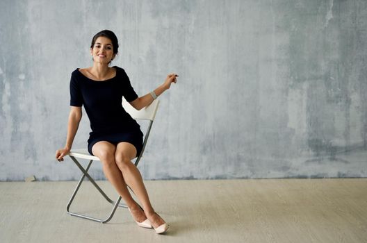 Woman in black dress sitting on chair posing luxury decoration fashion. High quality photo