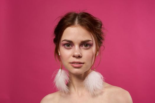 woman bare shoulders fluffy earrings bright makeup pink background. High quality photo