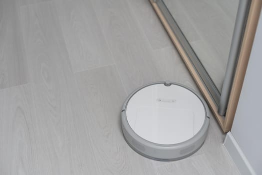 Robotic vacuum cleaner on laminate wood floor in bedroom