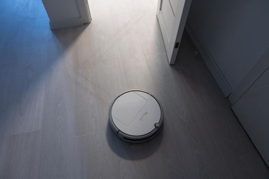 Robot vacuum cleaner performs automatic cleaning of the apartment at a certain time. Smart home.