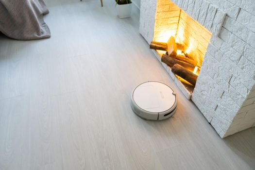 Smart House. Vacuum cleaner robot runs on wood floor in a living room.