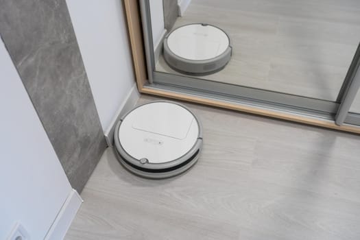 Robotic vacuum cleaner on laminate wood floor in bedroom