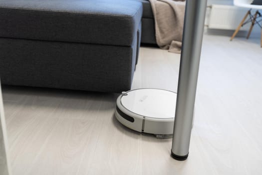 Robot vacuum cleaner cleaning kitchen floor.