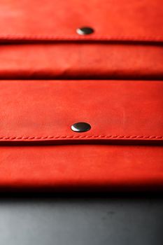 A pair of red genuine leather wallets with rivets on a dark background top view. Genuine leather, handmade