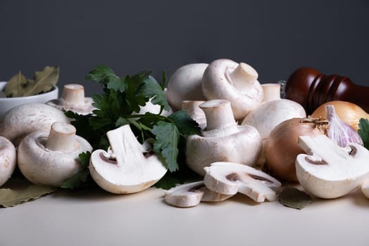 Bunch of raw champignons with other cooking ingredients on table. Mushrooms are like vegetable protein. The concept of vegetarian and vegan food. Cooking at home or in restaurant.