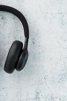 Wireless Black Headphones on a gray stone background. View from above. In-ear headphones for playing games and listening to music tracks. Modern style