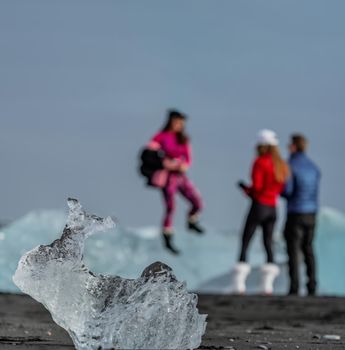 Blurred tourists in the background and iceberg with rabbit shape in focus