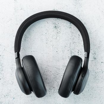 Wireless Black Headphones on a gray stone background. View from above. In-ear headphones for playing games and listening to music tracks. Modern style