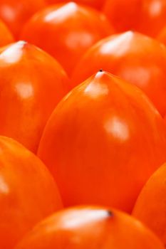 Fresh ripe persimmons in market. Persimmons background. Repeating rows of juicy, ripe persimmon in a box. Close-up, macro