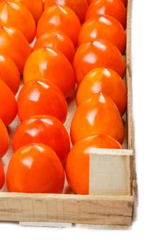 Persimmon fruit in the wooden box isolated on white. Clipping Path included. Juicy ripe persimmon in a large wooden box on a white background. Half wooden box, with space for text.