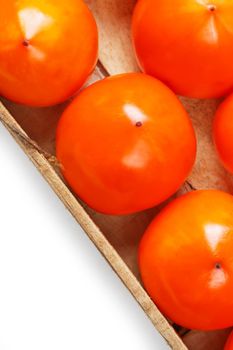 Fresh ripe persimmons in market. Persimmons background. Repeating rows of juicy, ripe persimmon in a box. Close-up, macro