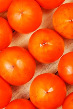 Fresh ripe persimmons in market. Persimmons background. Repeating rows of juicy, ripe persimmon in a box. Close-up, macro