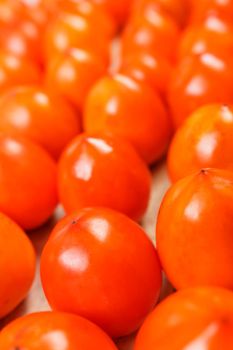 Fresh ripe persimmons in market. Persimmons background. Repeating rows of juicy, ripe persimmon in a box. Close-up, macro